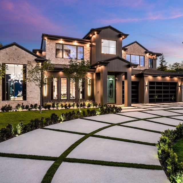Modern luxury home exterior at dusk with landscaped yard. Modern luxury home exterior with a beautifully landscaped front yard and driveway at dusk.